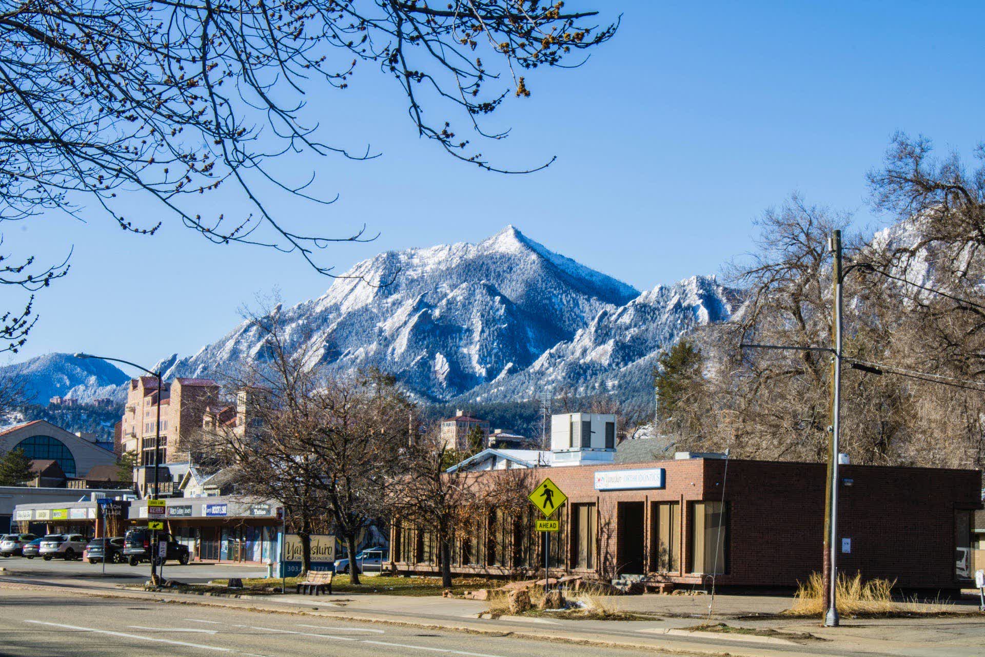 Boulder Colorado downtown street with snow-capped Flatirons rising in the background
