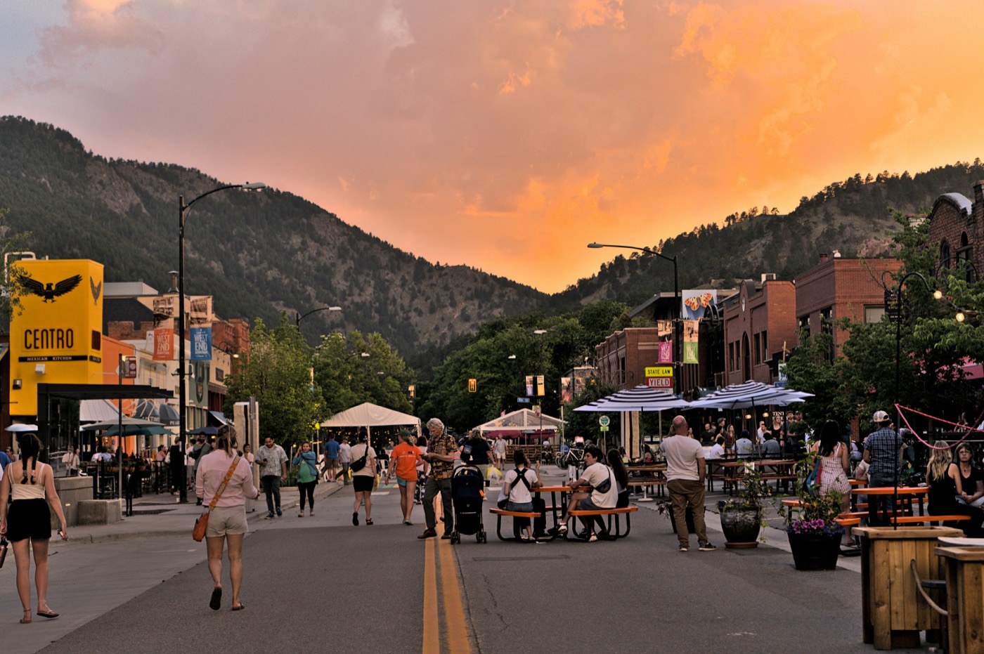Pearl Street outdoor dining and pedestrians at sunset with mountain backdrop, Boulder Colorado