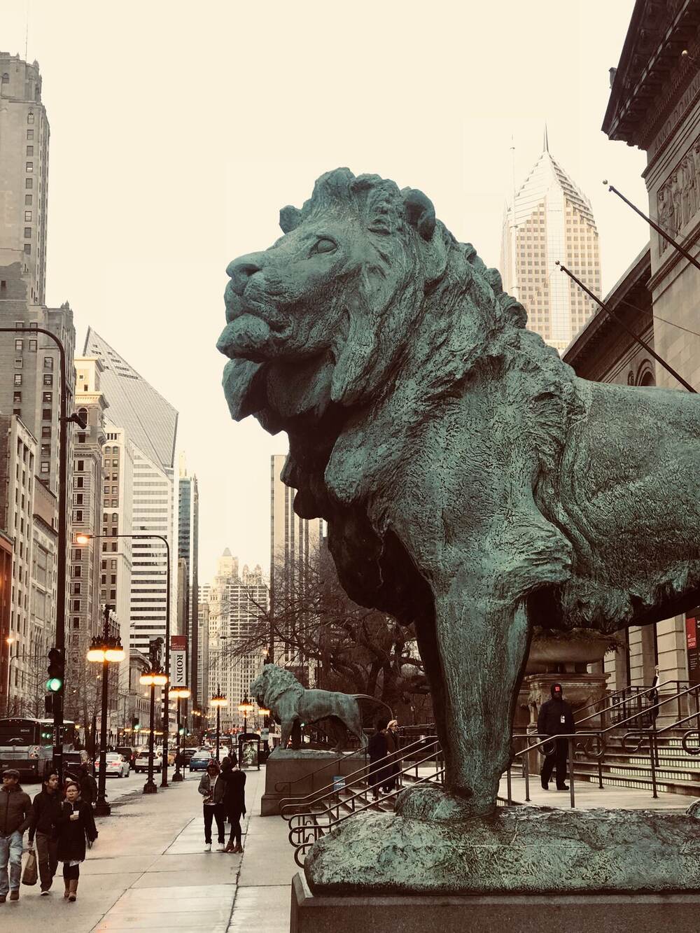 Bronze lion statue at the entrance to the Art Institute of Chicago with the city skyline behind