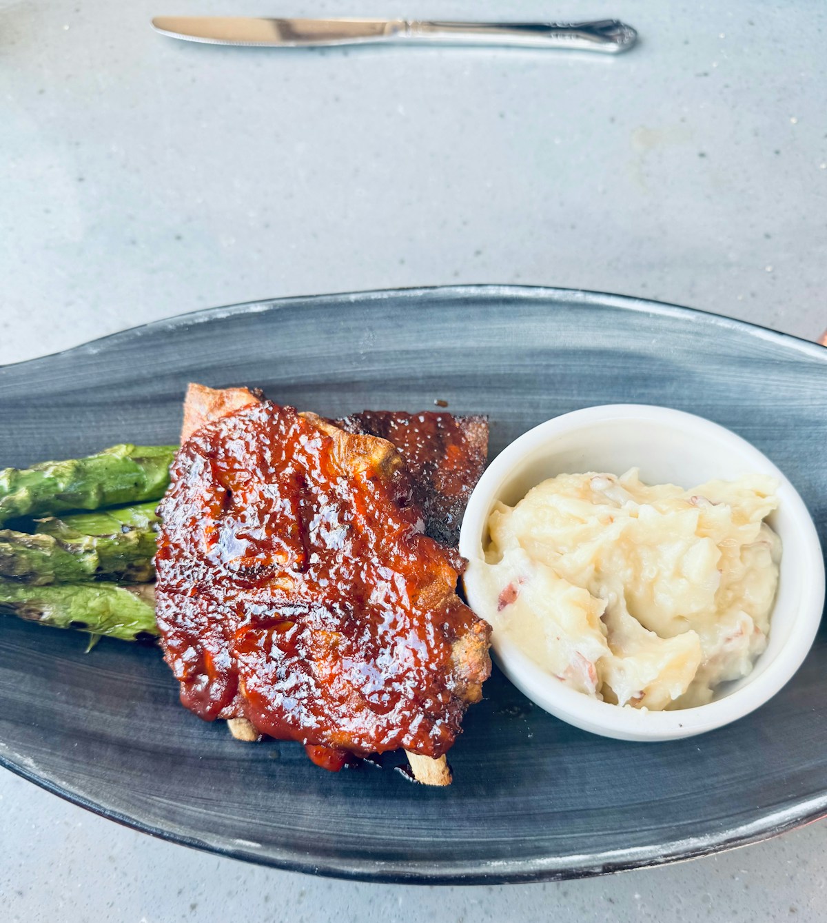 Rack of BBQ ribs with potato salad on a plate, American barbecue