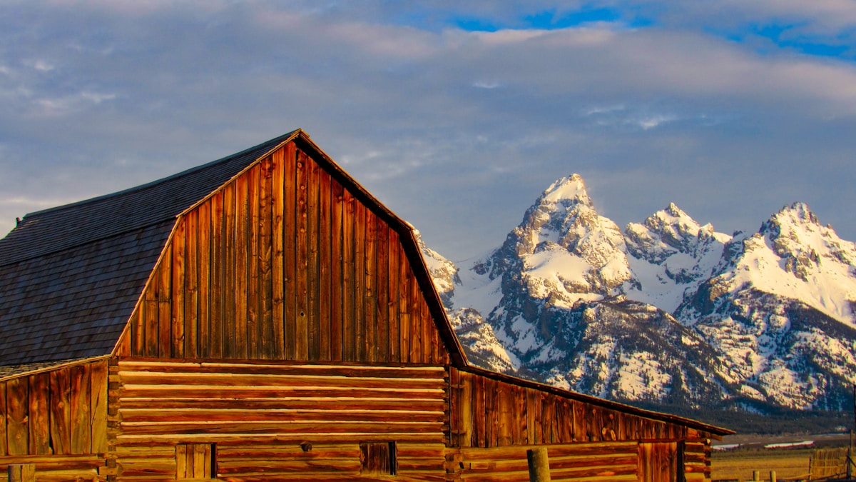 Weathered wooden barn in front of snow-capped Grand Teton peaks, Mormon Row, Wyoming