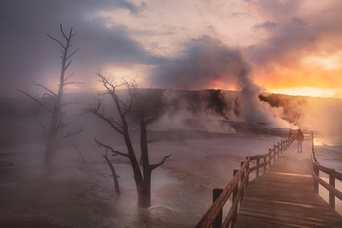 Person standing near a steaming geyser, Yellowstone National Park, Wyoming