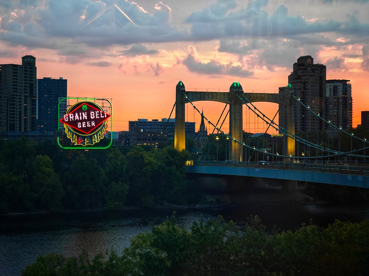 City skyline with a bridge and neon beer sign at sunset - Minneapolis dining scene, Minnesota
