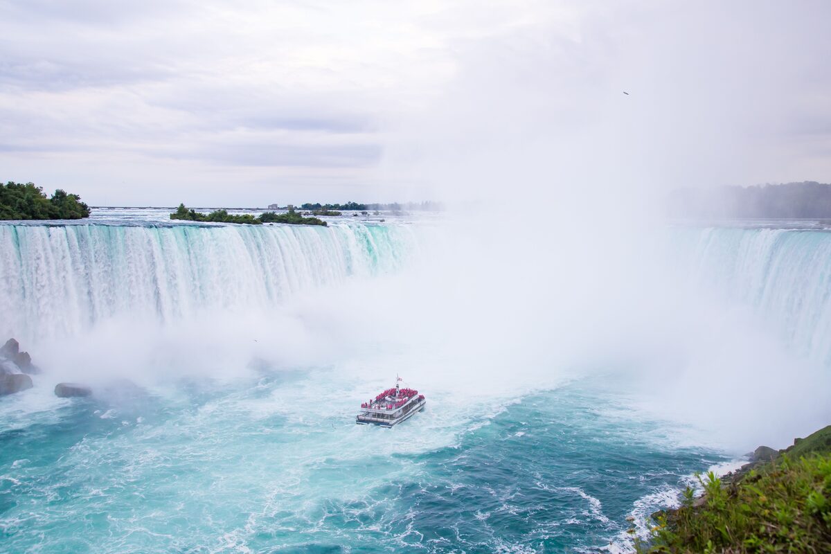 Tour boat navigating the misty turquoise waters below the Horseshoe Falls at Niagara Falls