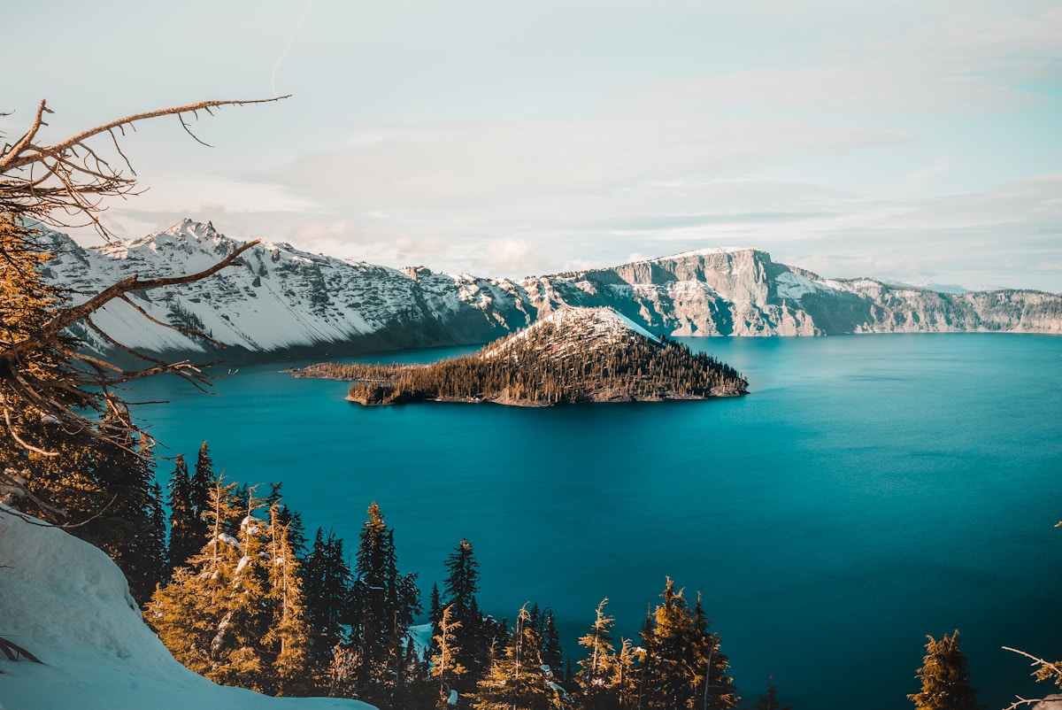Wizard Island rising from the deep-blue water of Crater Lake, Oregon, with snow-capped caldera walls