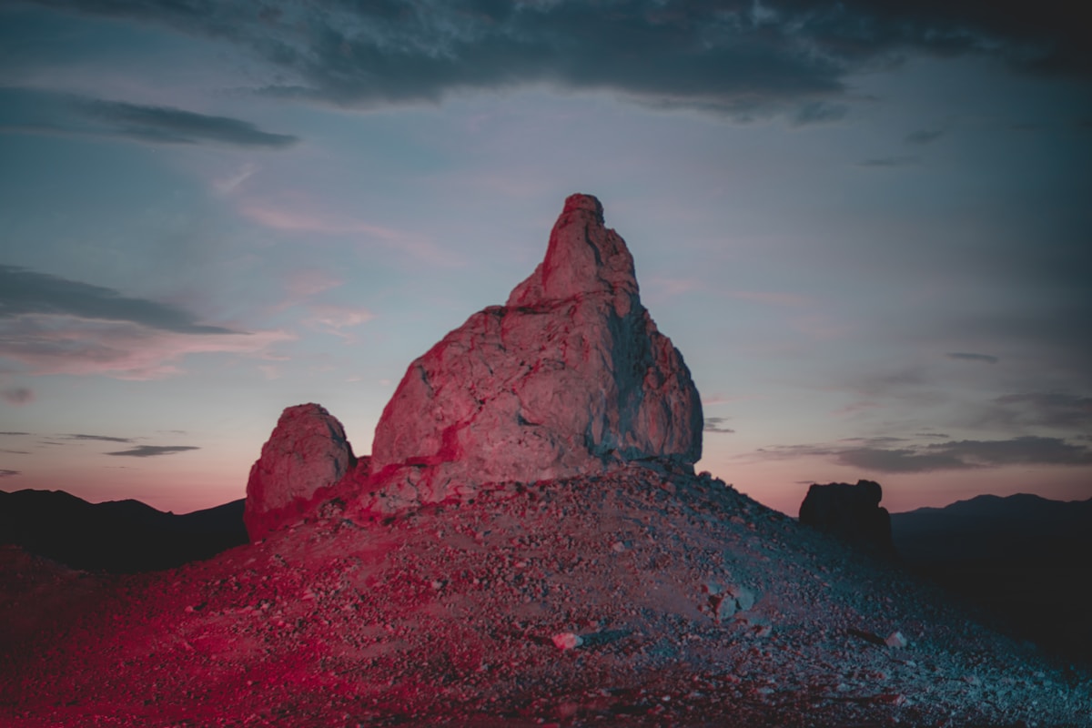 Dramatic volcanic rock spire formation glowing at sunset against a colorful sky, California