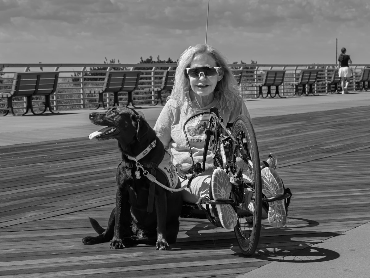 Woman in handcycle with service dog on the Long Beach boardwalk, New York, USA