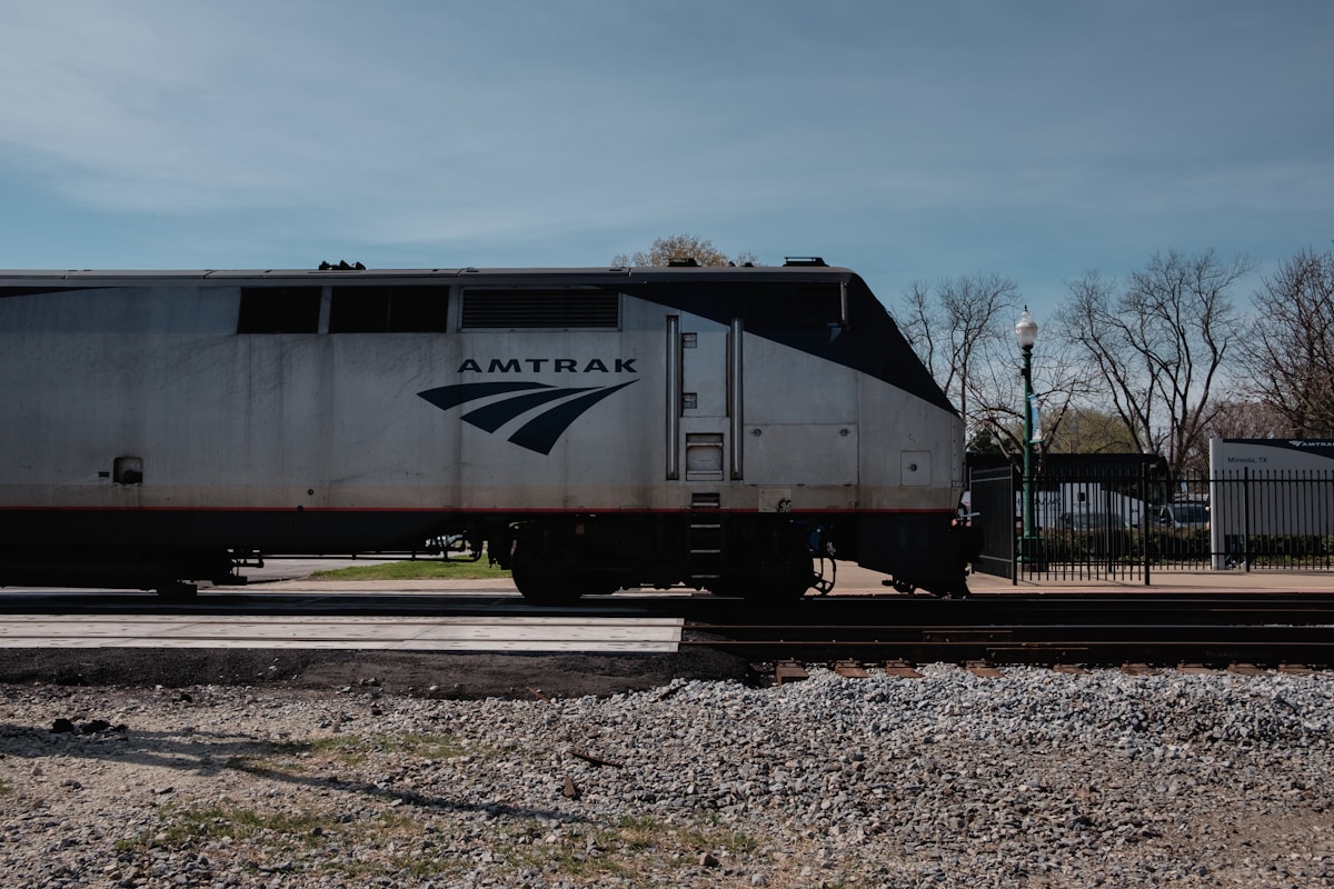 Amtrak long-distance locomotive passing a small-town station crossing