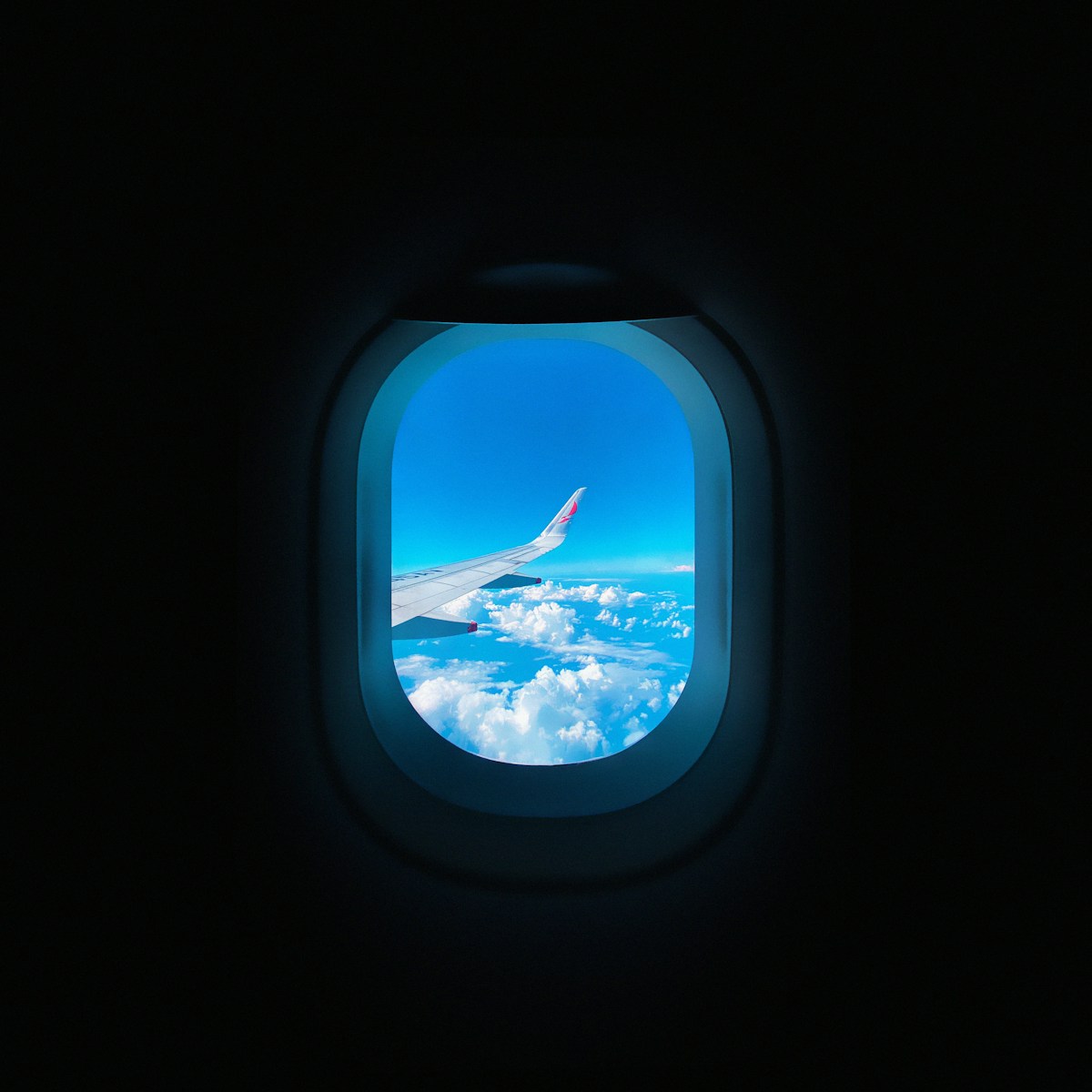 Airplane wing above clouds seen through a cabin window