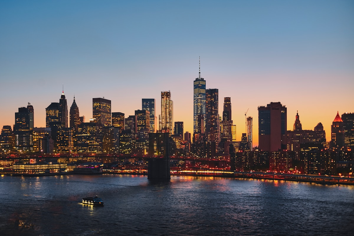 Manhattan skyline at dusk with the Brooklyn Bridge in the foreground