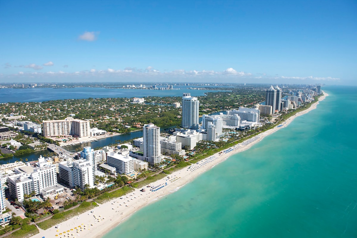 Aerial view of Miami Beach coastline with white buildings and turquoise ocean water
