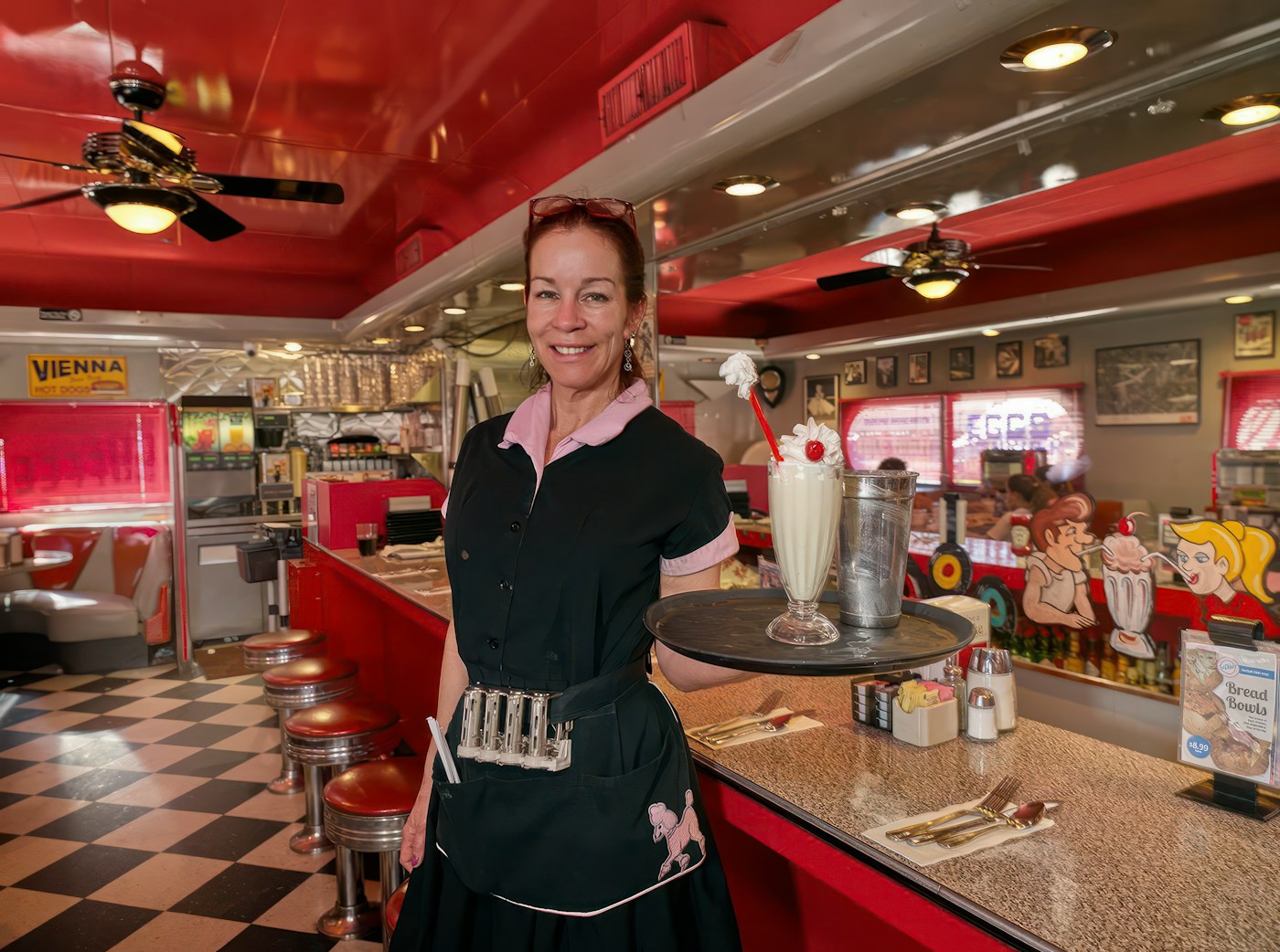 Waitress holding a milkshake at a classic 1950s diner counter, Phoenix, Arizona