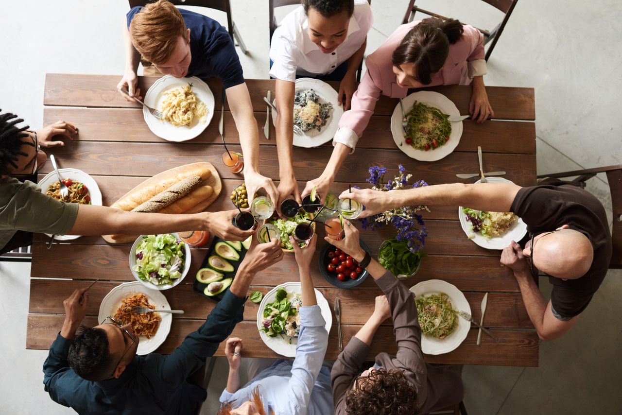 Group of friends raising glasses in a toast around a dining table, USA