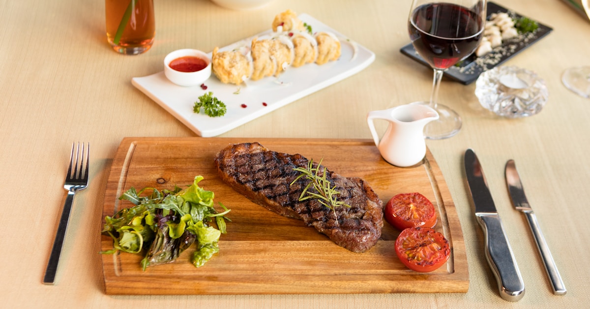 Grilled steak on a wooden board with salad and red wine at an American steakhouse