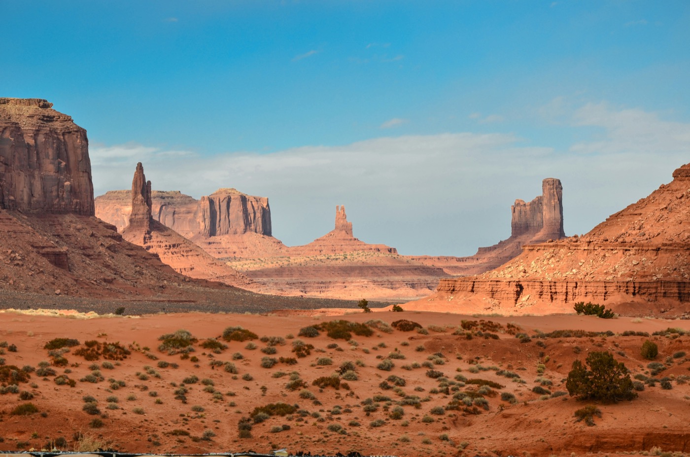 Open desert highway leading toward Monument Valley rock formations at sunset