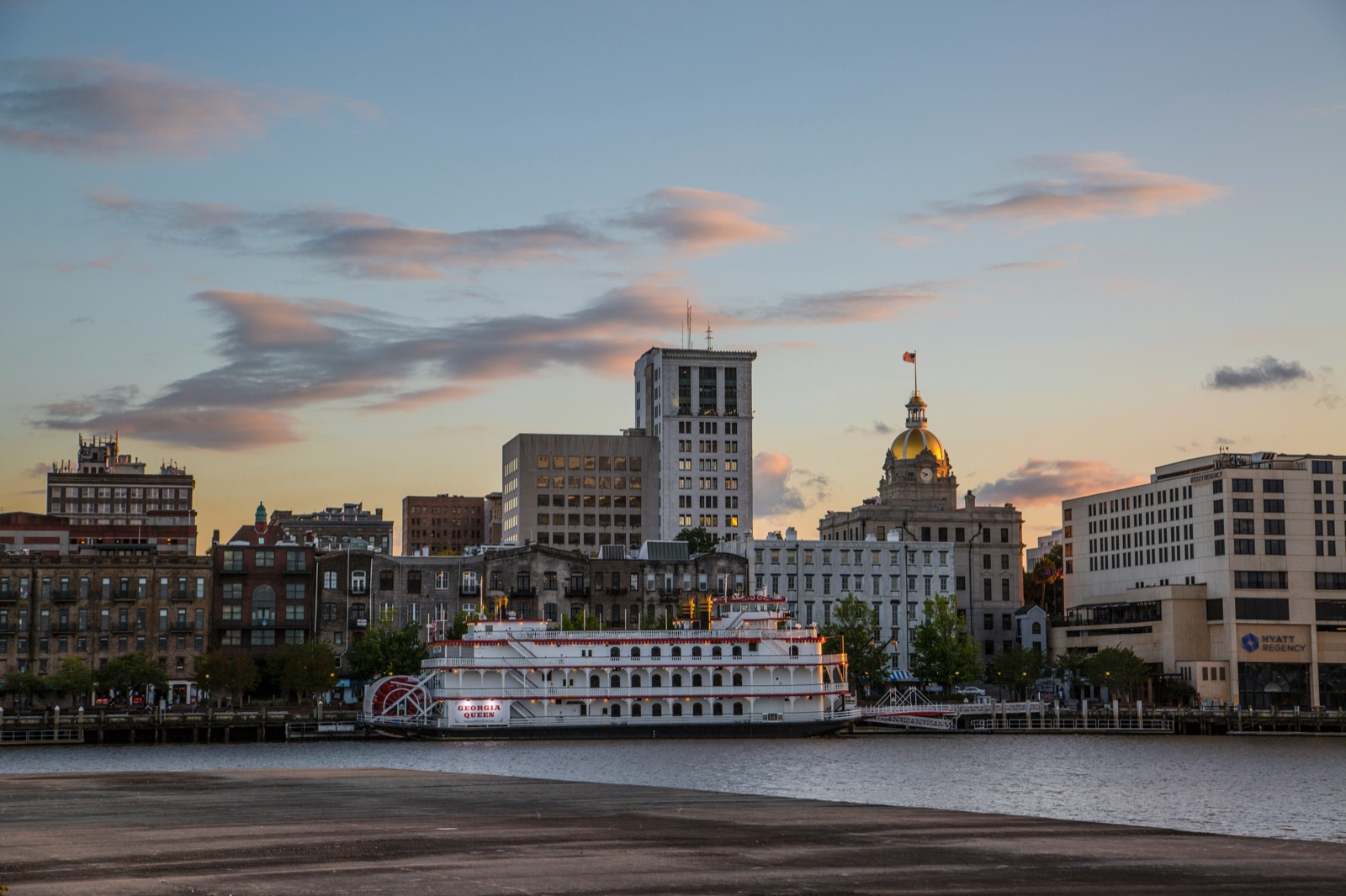 Boat on the water near Savannah city buildings at sunset, Georgia